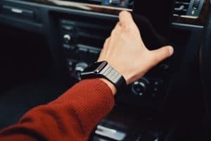 person with watch grabbing cell phone in a car